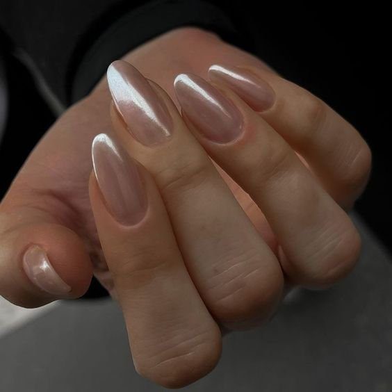 Unhas bem cuidadas com esmalte perolado em fundo escuro.