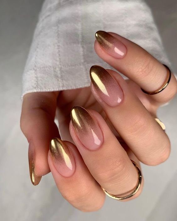 ombre Unhas com esmalte em tons de dourado e rosa, decoradas com anéis dourados.