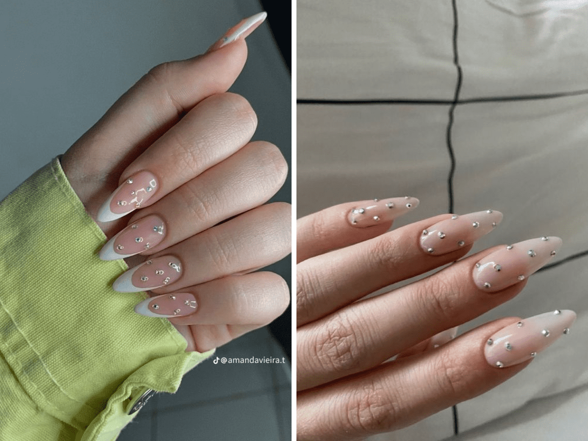 Unhas decoradas com esmalte claro, pedrinhas brilhantes e pontas brancas em formato amendoado.