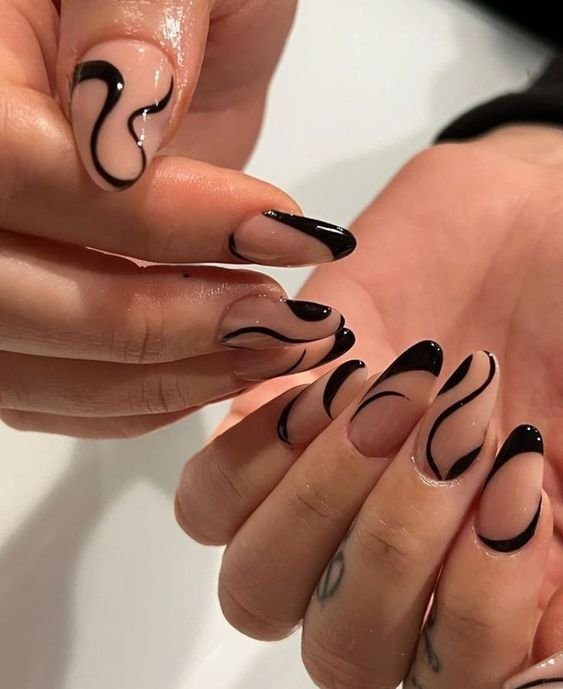 Mãos com unhas decoradas em tons de nude e preto, com design abstrato e moderno.