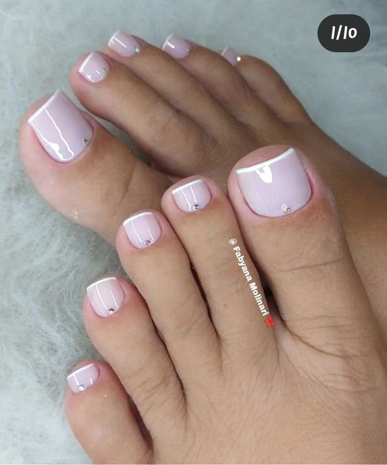 Unhas dos pés com esmalte rosa claro e detalhes decorativos.
