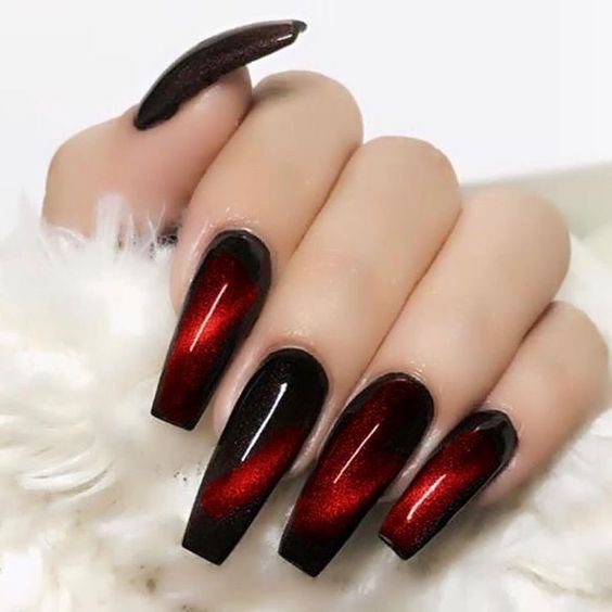 2cd9677ac5aa696f0a275b79244747e0 Unhas compridas com esmalte vermelho e preto, em fundo claro.