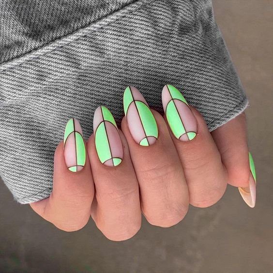 6a3854a6ea8971ea16e7b49b4e6e8d69 Unhas com design geométrico em verde neon e nude, destacadas por linhas pretas, segurando tecido cinza.
