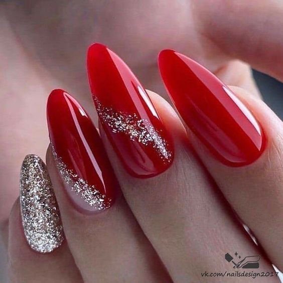 Unhas longas com esmalte vermelho e detalhes em glitter dourado.