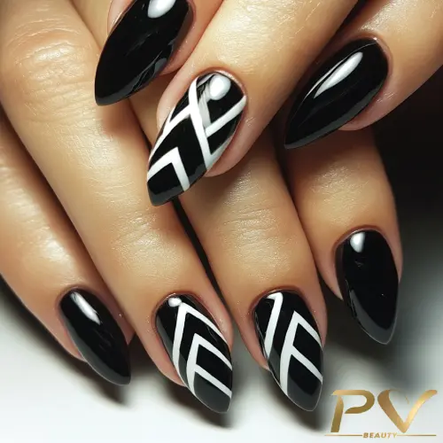 Unhas pintadas de preto com detalhes geométricos em branco, formando um padrão moderno e elegante.