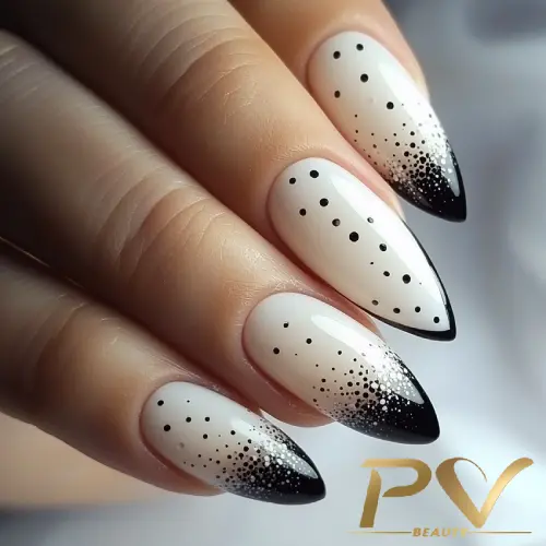 Unhas decoradas em formato stiletto com esmalte branco, detalhes em preto e pontos gradientes.