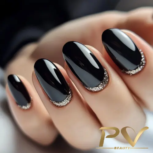 Unhas com esmalte preto e bordas decoradas com glitter prateado.