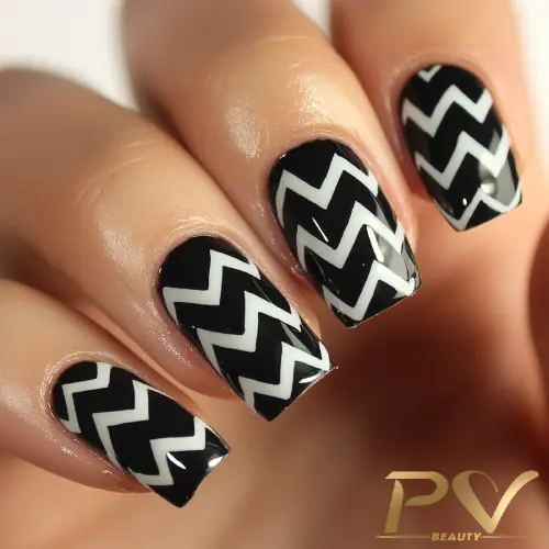 Unhas decoradas com esmalte preto e padrão de zigue-zague branco.