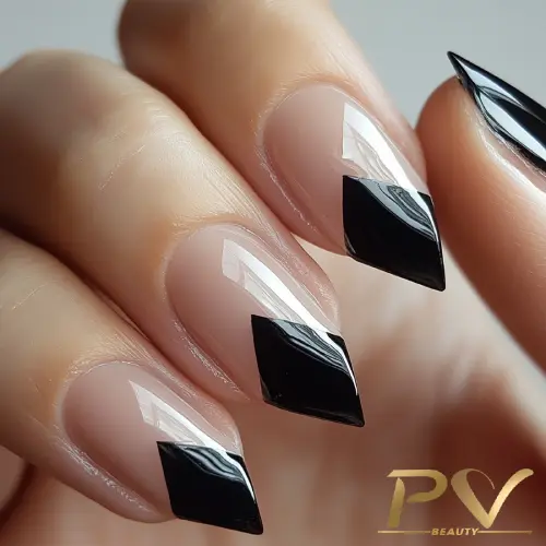 Unhas em formato stiletto com design geométrico preto sobre base nude.