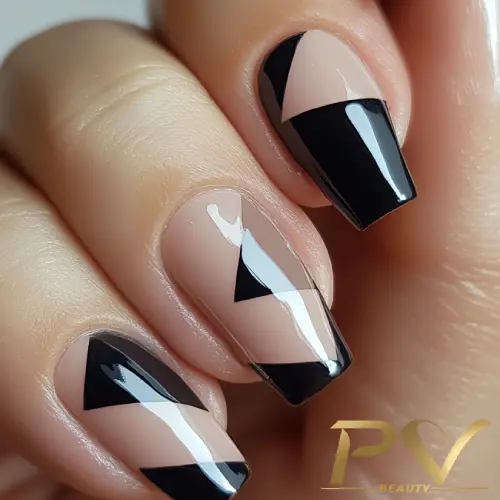 Unhas decoradas com esmalte nude e preto, formando padrões geométricos elegantes e modernos.