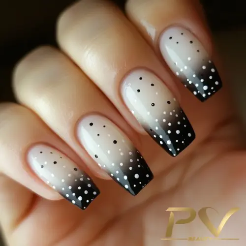Unhas com esmalte em degradê preto e pontilhado branco, exibindo um design elegante e moderno.