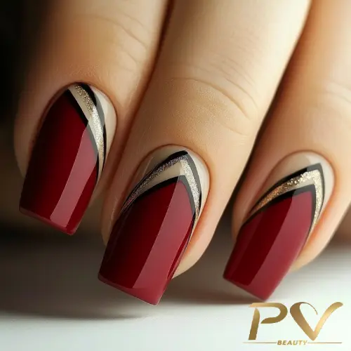Unhas decoradas com esmalte vermelho, preto e dourado, exibindo um design geométrico sofisticado.