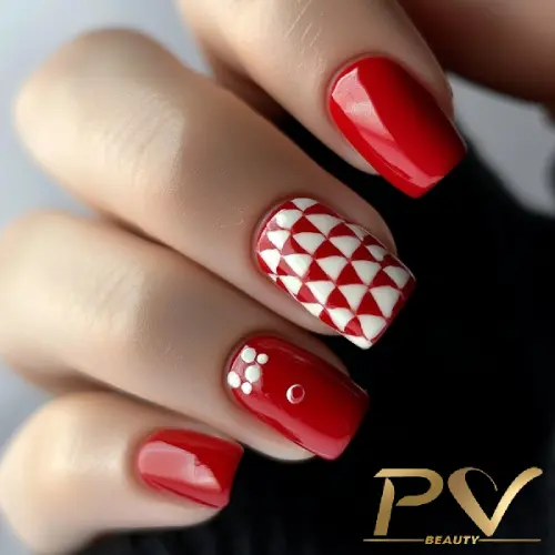 Unhas pintadas de vermelho com detalhes geométricos e florais brancos em dois dedos. Fundo neutro.