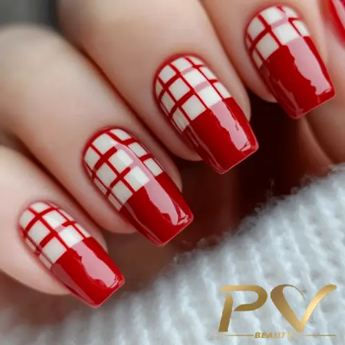 Unhas decoradas com esmalte vermelho e padrão quadriculado branco, capturadas de perto.