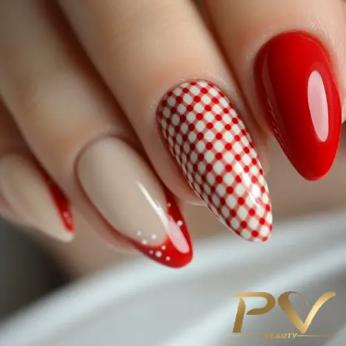 Mão com unhas decoradas em vermelho e bege, com design xadrez e pontinhos brancos.
