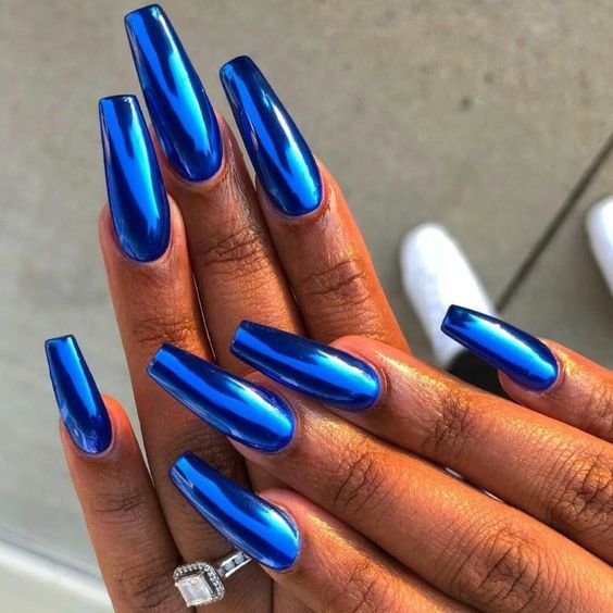 e576f5e40516a63c6542dd70cf93fd1b Unhas longas com esmalte azul metálico brilhante. Mão com anel quadrado.