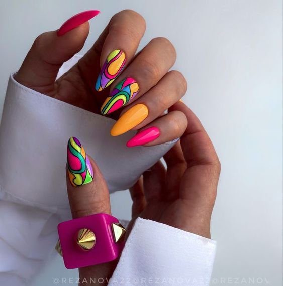 fd7d6cfa97610f4957a3c3fe1b4b19ef Mãos com unhas longas e coloridas, exibindo diferentes designs vibrantes e acessórios modernos.