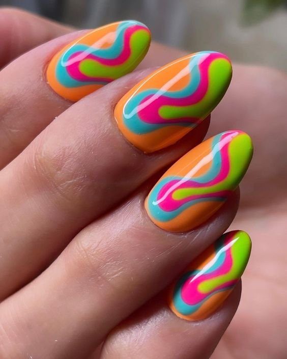 ondas-coloridas-um-classico-do-carnaval Unhas decoradas com esmalte laranja, rosa, azul e verde em um design ondulado e colorido.