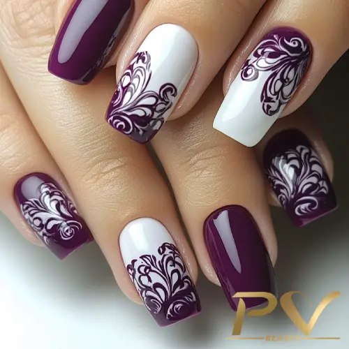 roxo-unhas-arabescos-decoradas-pv-beauty-05 Unhas decoradas com esmalte roxo e branco, apresentando desenhos florais detalhados em algumas delas.