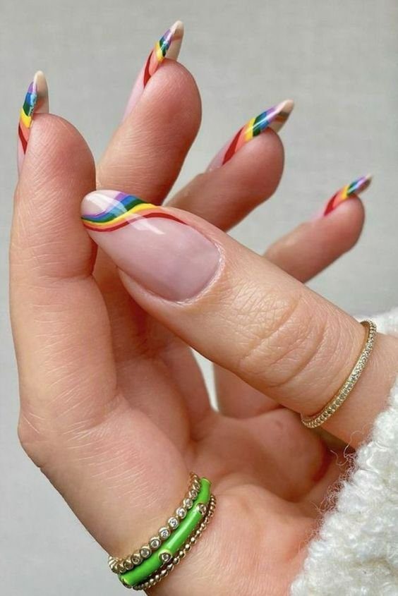 um-arco-iris-mais-minimalista-tambem-se-encaixa-bem-entre-as-inspiracoes Unhas decoradas com listras coloridas em estilo arco-íris, com anéis dourados e verdes no dedo.