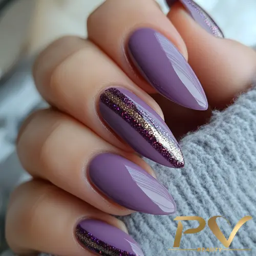 unha-de-gel-perto-de-mim-decorada-lilas-glitter-pv-beauty-06 Unhas pintadas de lilás com detalhes em glitter dourado e roxo escuro, sobre fundo cinza.