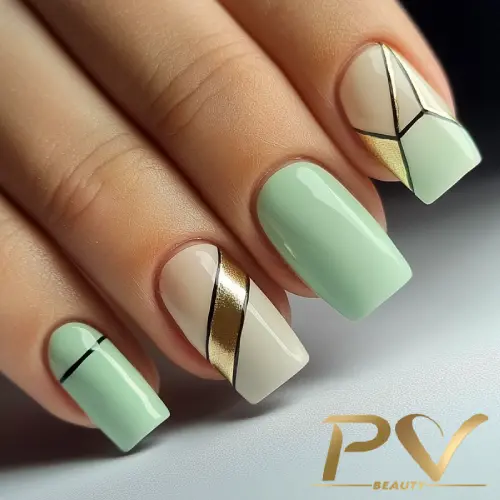 Unhas decoradas com esmalte verde e nude, com linhas diagonais douradas e pretas em design geométrico.