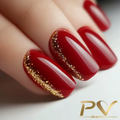 Unhas pintadas de vermelho com detalhes em glitter dourado nas bordas, mostrando um design elegante e brilhante.