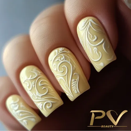 unhas-amarelas-arabescos-suaves-decoradas-pv-beauty-18 Unhas em tom amarelo claro com detalhes em relevo de padrão floral branco.