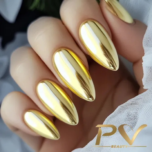 unhas-amarelas-metalizadas-decoradas-pv-beauty-23 Unhas longas com esmalte dourado metálico, refletindo luz, em uma mão segurando tecido branco.