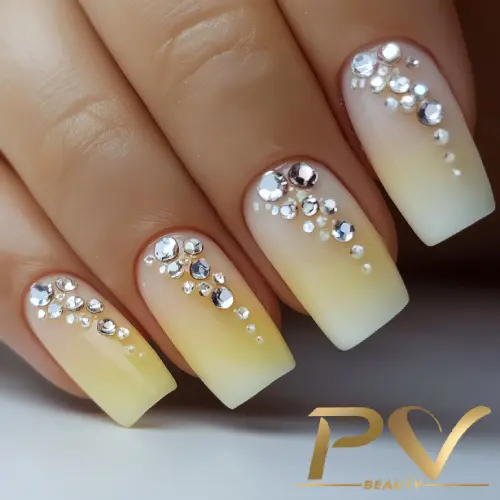 unhas-amarelas-ombre-strass-decoradas-pv-beauty-06 Unhas decoradas em degradê amarelo e branco com aplicação de pequenas pedras brilhantes.