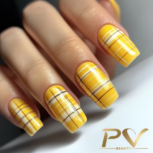 unhas-amarelas-quadriculado-decoradas-pv-beauty-20 Unhas decoradas com esmalte amarelo e padrão xadrez branco e marrom, exibindo um design elegante e moderno.