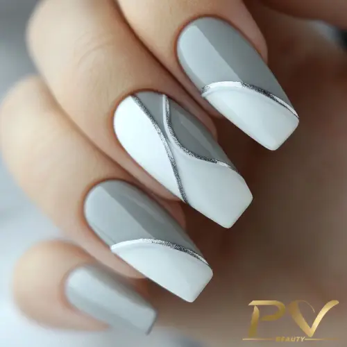 unhas-cinza-decoracao-curvas-geometricas-nail-art-pv-beauty-22 Unhas com esmalte cinza e branco, decoradas com linhas prateadas, em design geométrico moderno.