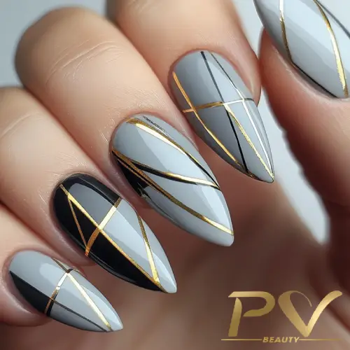 unhas-cinza-decoracao-linhas-douradas-modernas-pv-beauty-30 Unhas decoradas com esmalte cinza e preto, com listras douradas formando padrões geométricos.