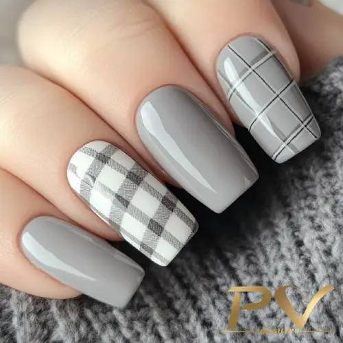 unhas-cinza-decoradas-xadrez-nail-art-pv-beauty-15 Unhas pintadas de cinza, com duas em padrão xadrez preto e branco, sobre fundo de tecido cinza.