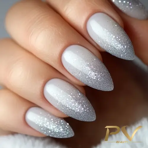 unhas-cinza-glitter-ombre-pv-beauty-03 Unhas com esmalte branco e gradiente prateado brilhante, em formato amendoado.