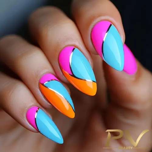 Unhas decoradas com esmalte colorido em tons de azul, rosa e laranja, com detalhes metálicos prateados.
