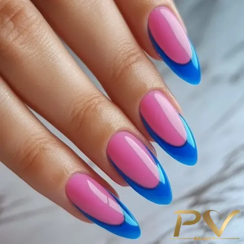 Mão com unhas longas e pontudas em tons de rosa e azul, sobre superfície clara.