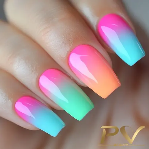 Unhas com esmalte em degradê de tons vibrantes de rosa, laranja, verde e azul.