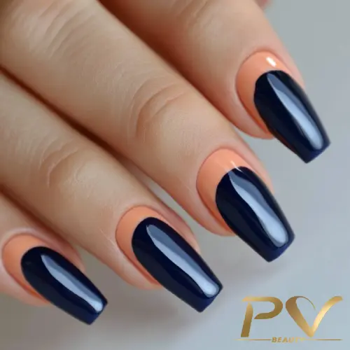 Unhas com esmalte azul escuro em design geométrico sobre base nude, destacando formato alongado e bem cuidado.