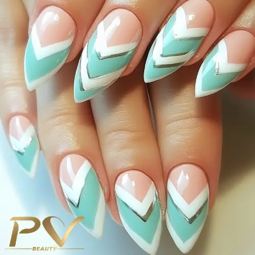 Unhas decoradas com padrões geométricos em tons de azul, branco e prata, com acabamento brilhante.