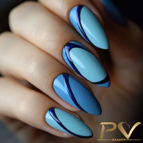 unhas-decorada-azul-curvas-tom-sobre-tom-pv-beauty-18 Unhas compridas com esmalte azul e detalhes geométricos escuros, destacando um design elegante e moderno.