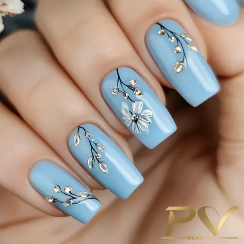 unhas-decorada-azul-floral-suave-pv-beauty-20 Unhas com esmalte azul claro, decoradas com desenhos de flores e ramos dourados.