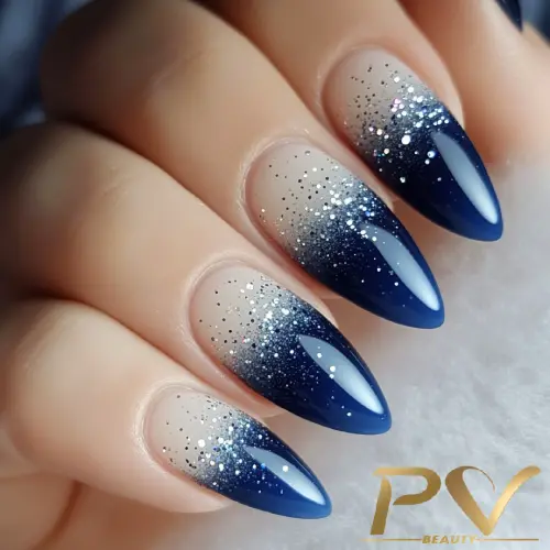 unhas-decorada-azul-ombre-glitter-pv-beauty-17 Unhas com esmalte azul e efeito degradê prateado com glitter, em formato pontiagudo.