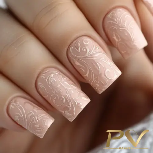 Unhas decoradas com esmalte nude e detalhes em relevo floral.