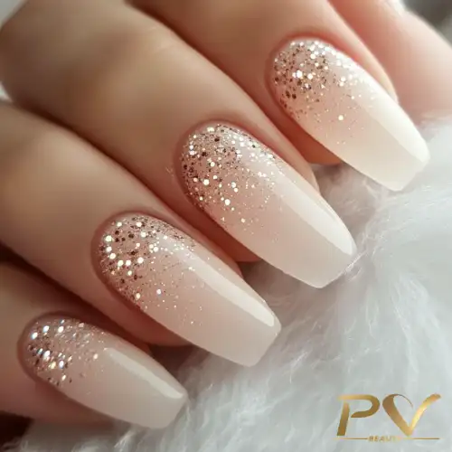 Unhas decoradas bege com efeito ombré e glitter, tendência moderna em nail art.