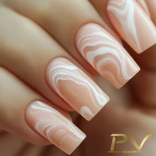Unhas decoradas com esmalte nude e detalhes em linhas brancas onduladas.