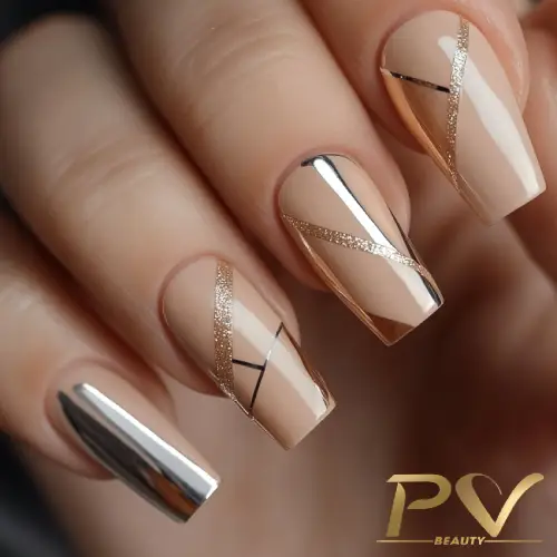 Unhas decoradas com esmalte nude, detalhes metálicos e linhas douradas e pretas.