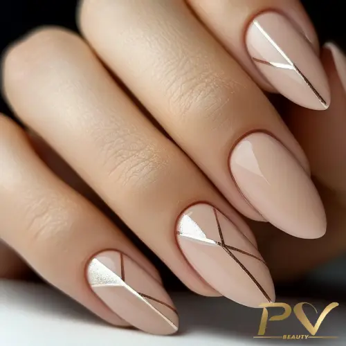 Unhas com esmalte nude e detalhes metálicos em linhas diagonais.