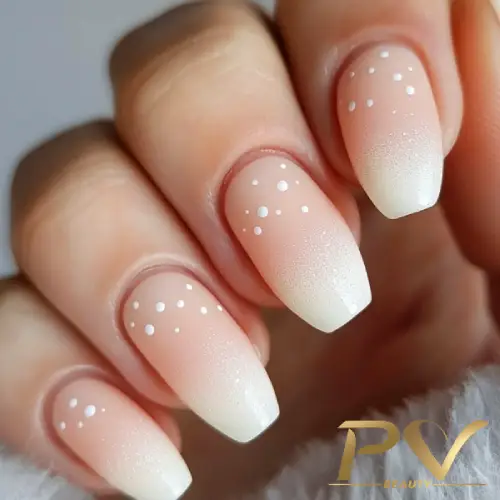 Unhas com esmalte ombré rosa claro e branco, decoradas com pequenos pontos brancos.
