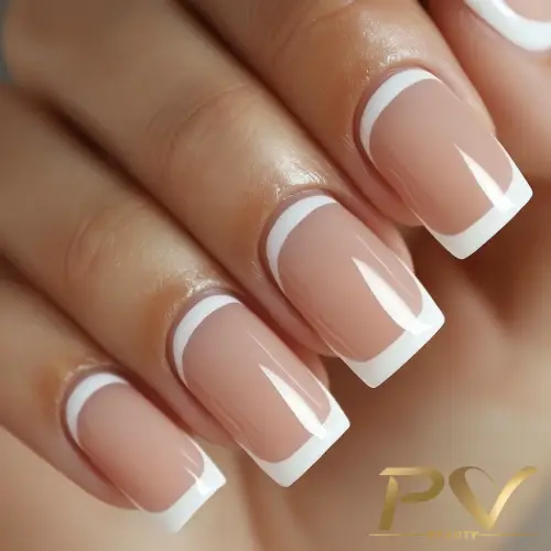 Unhas decoradas com esmalte nude e pontas brancas, estilo francesinha, com acabamento brilhante.